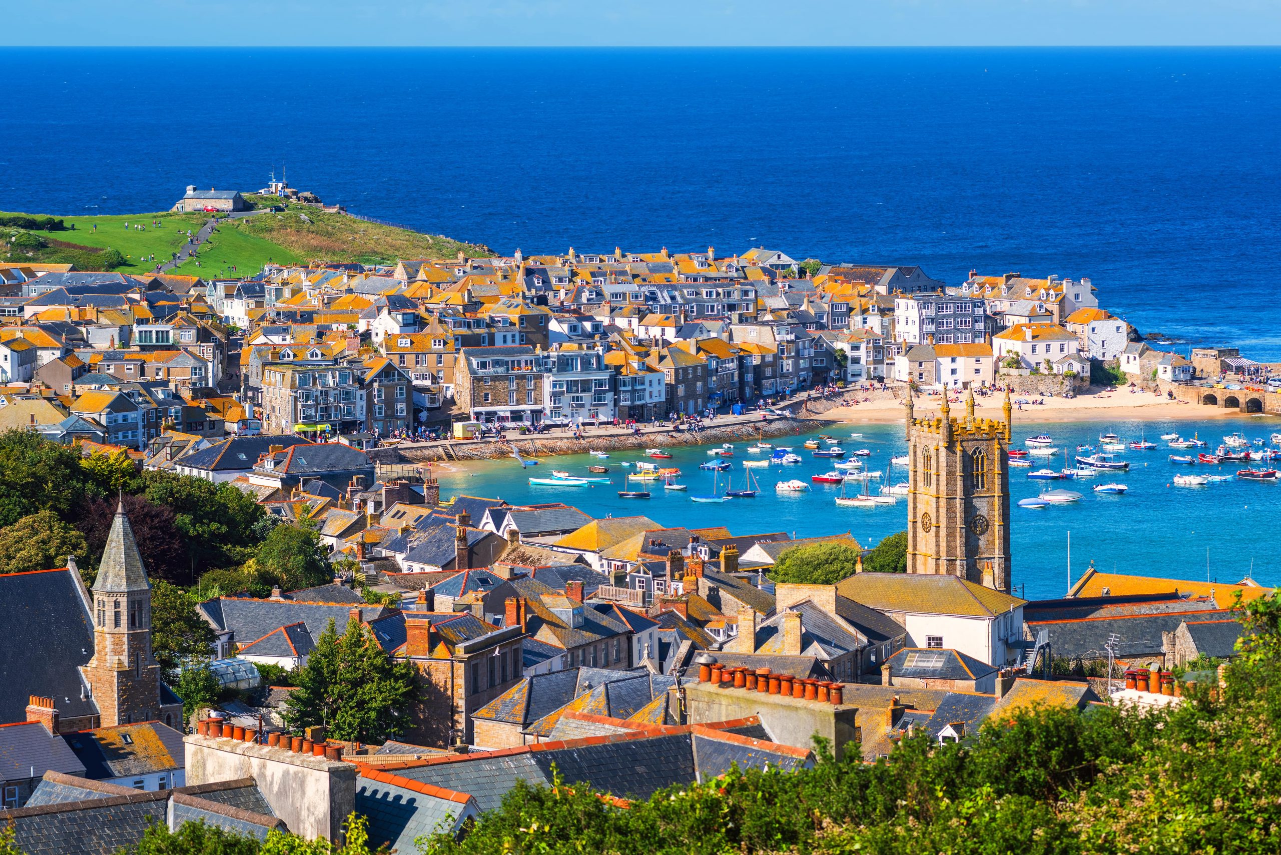 idyllic view across a cornish coastal village and bay brimming with fishing boats