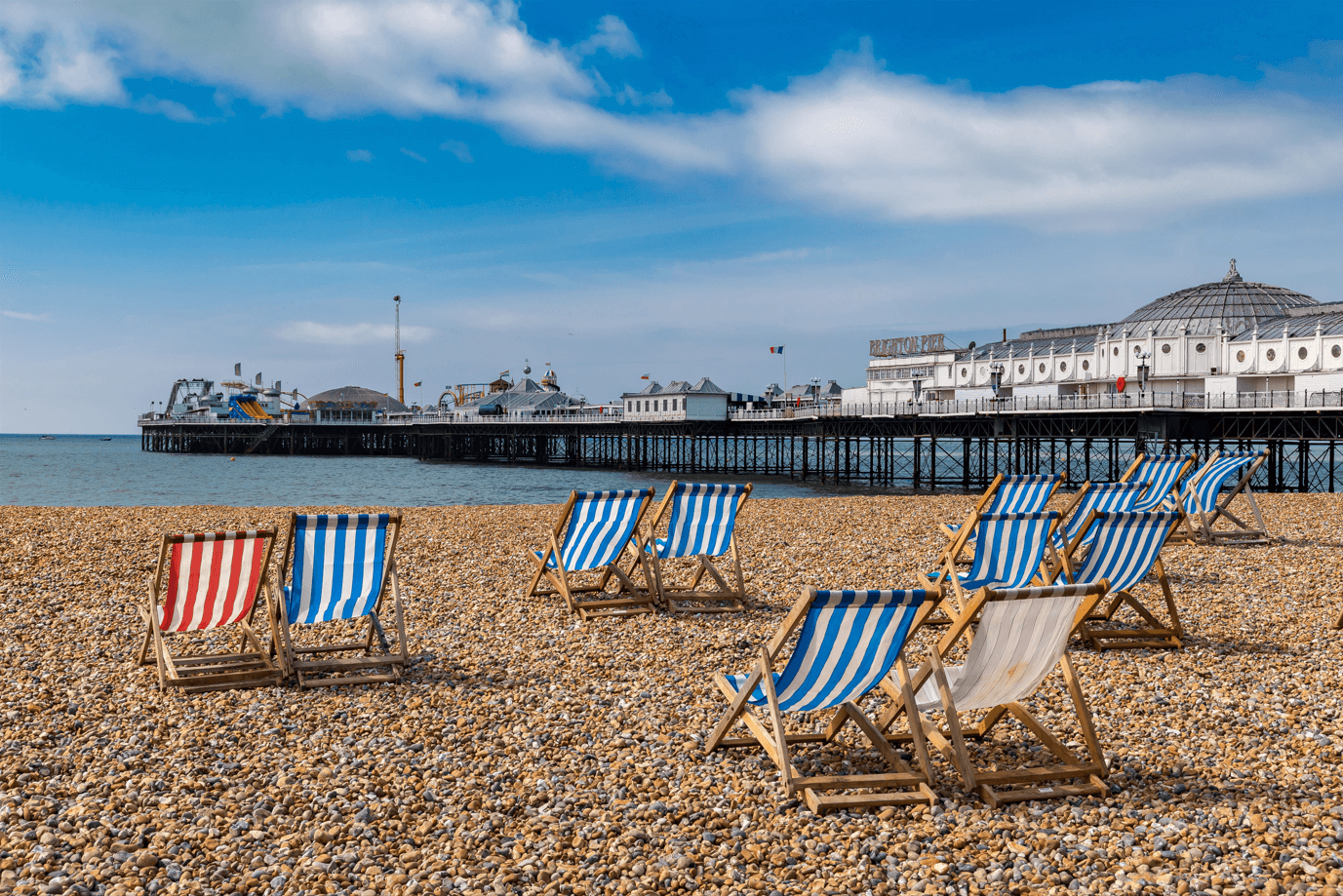 deck chairs laid out on brighton beach across from brighton pier