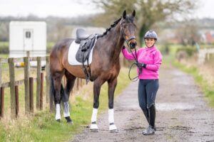 Woman holding horse tacked up and ready to ride